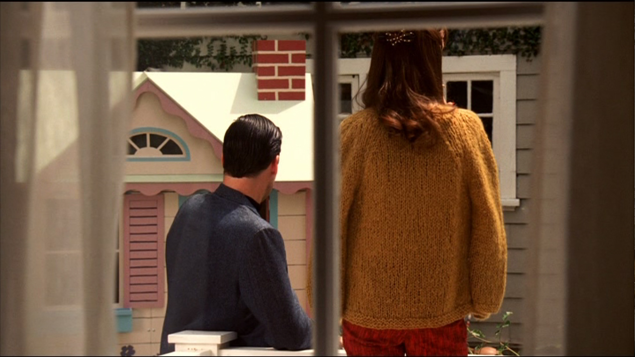 Don Draper et Helen Bishop (Darby Stanchfield) prennent l’air dans le jardin, devant la fenêtre de la cuisine où se trouvent les épouses